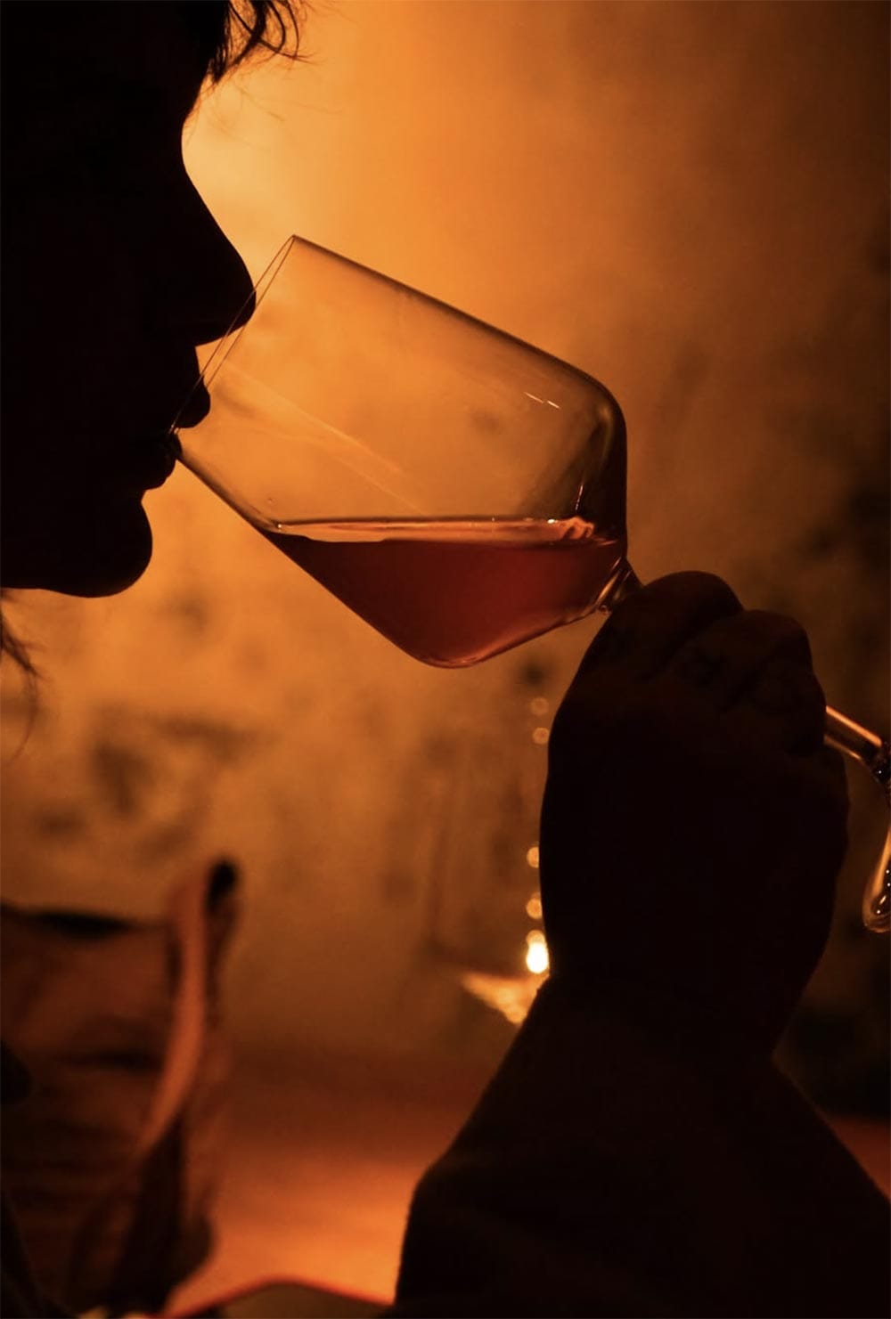 Une cliente goûte un verre de vin dans la lumière ambrée